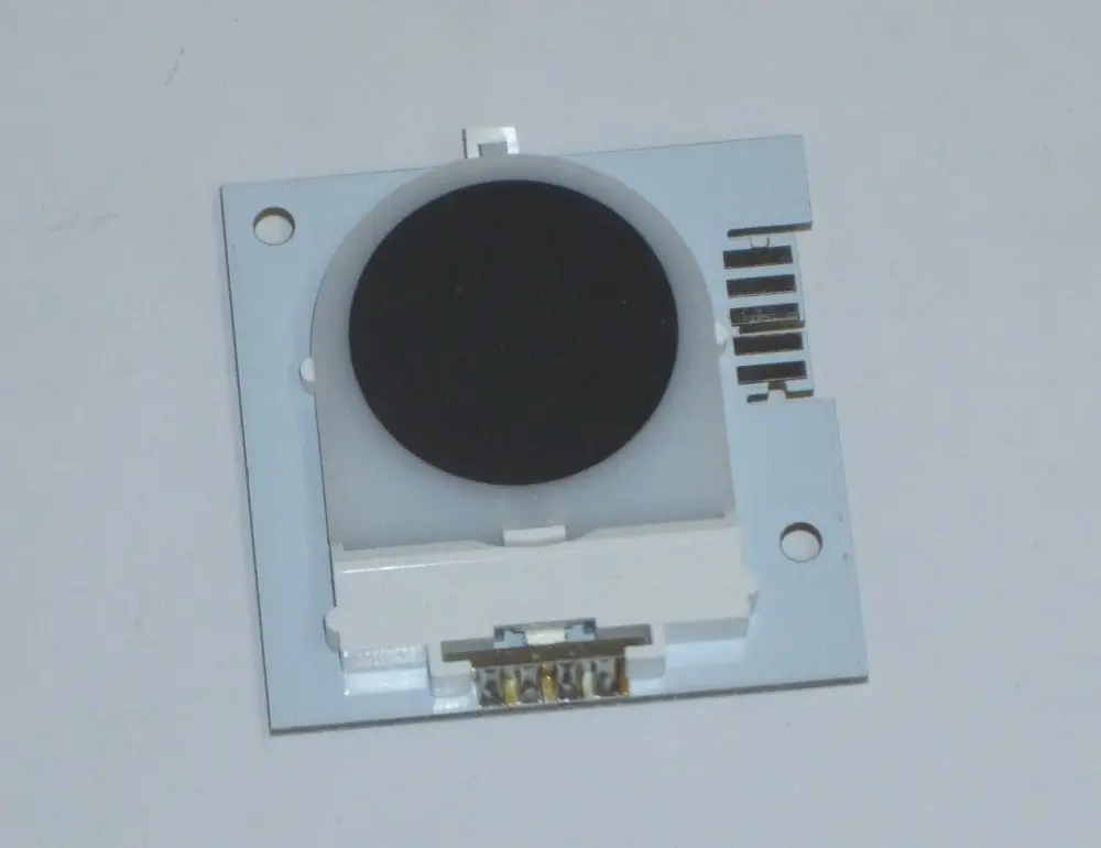 Schwarze runde Linse auf einer weißen Platine mit Anschlüssen, möglicherweise Teil eines Daikin-Produktes.